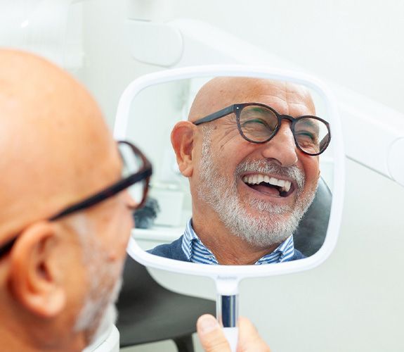 Male patient smiling and listening to dentist explain dental implant care in Channahon