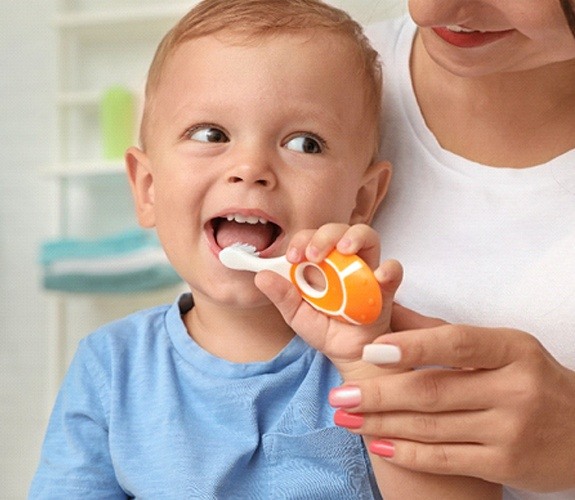 Mother holding child who is brushing their teeth