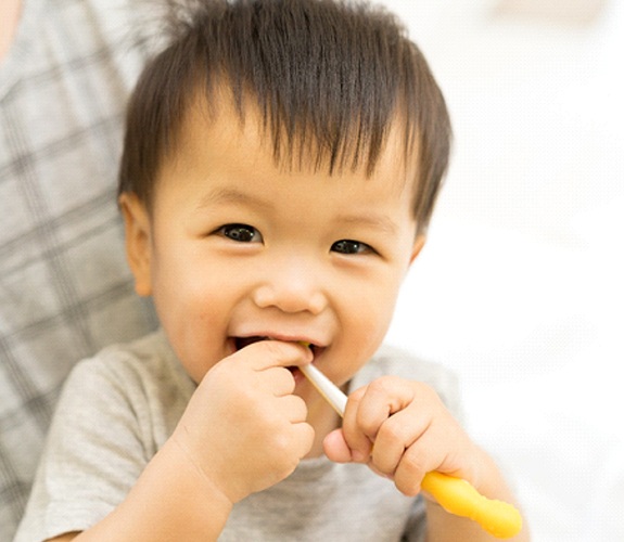 Little boy smiling and putting toothbrush in mouth