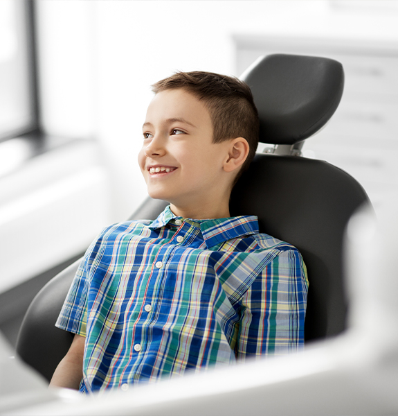 Child in dental chair smiling at dentist