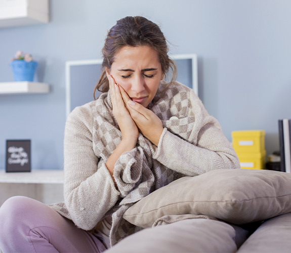 Woman in need of emergency dentistry holding cheek