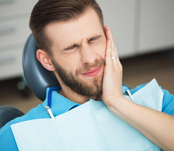 Man in need of emergency dentistry holding cheek