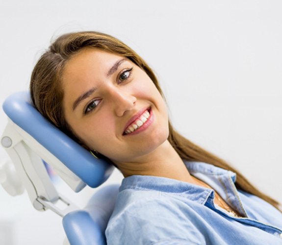 Female dental patient leaning back in chair and smiling