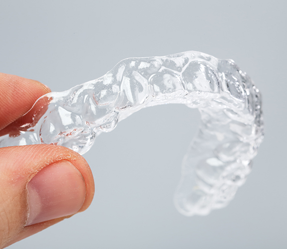 Hand holding an Invisalign tray