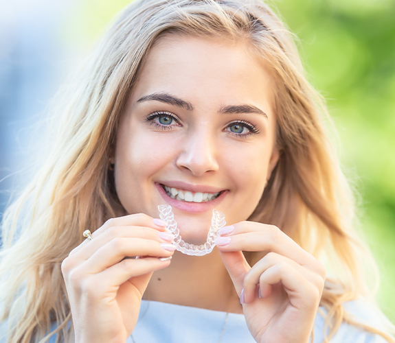 Young girl placing an Invisalign Teen clear braces tray