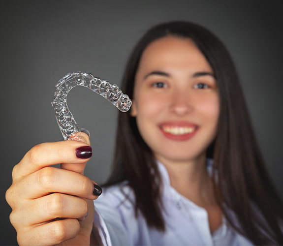 Woman holding up an Invisalign tray