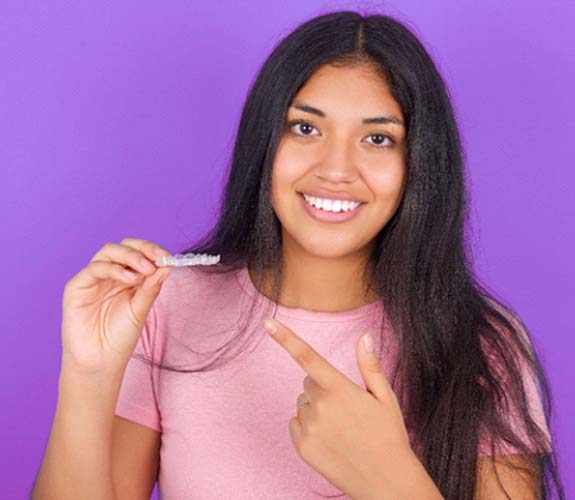 Teeth holding Invisalign Teen aligner in Channahon