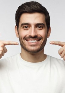 a man smiling and pointing at his teeth
