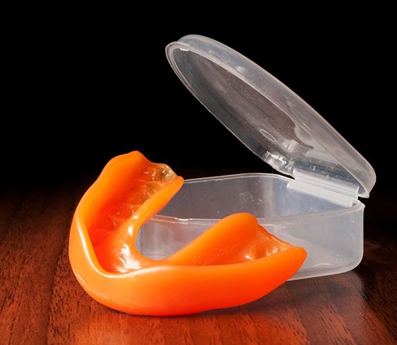 Teen with athletic mouthguard hanging from football helmet