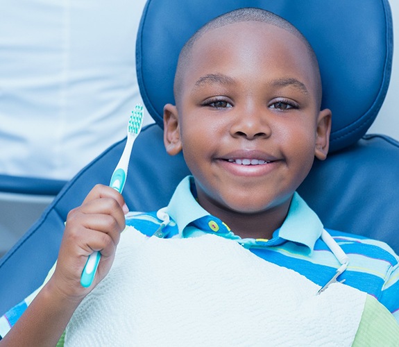 Young boy holding toothbrush after consultation for Phase 1 orthodontics in Channahon, IL