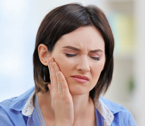 Woman in need of T M J treatment holding jaw
