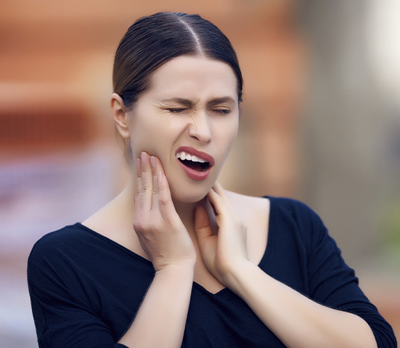 Woman in need of root canal therapy holding jaw in pain