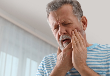 Man in need of emergency dentistry holding cheek in pain