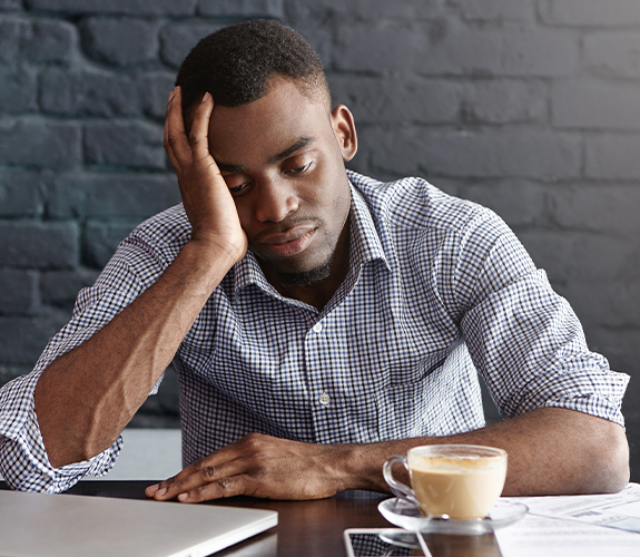 Man in need of sleep apnea treatment feeling tired at work