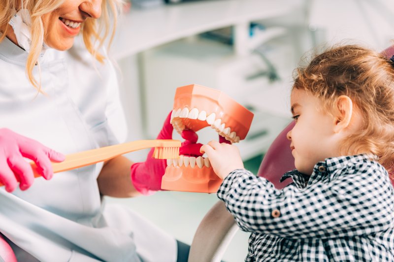 Little girl learning how to brush at the dentist’s office