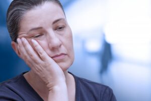 older woman holding her face and appearing fatigued